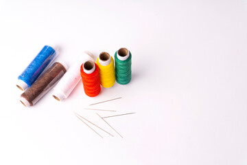 Colorful sewing thread set and needles isolated on background.