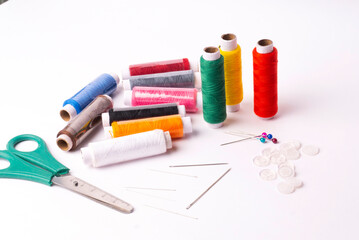 Colorful sewing thread set and needles isolated on background.