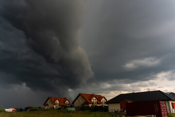 Dark storm clouds forming over suburban houses in the countryside.