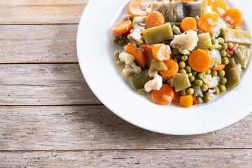 Vegetable stew (menestra de verduras) on wooden table. Copy space