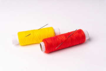 Colorful sewing thread set and needles isolated on background.