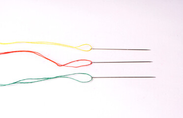 Colorful sewing thread set and needles isolated on background.