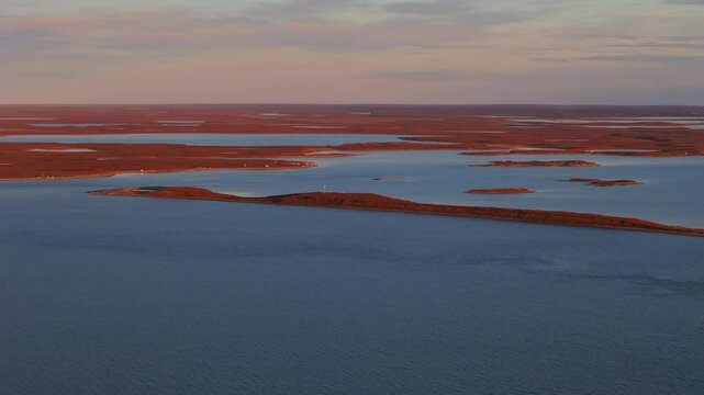 Sunset View Of Tuktoyaktuk On Kugmallit Bay Near Mackenzie River Delta, Northwest Territories, Canada. wide drone shot