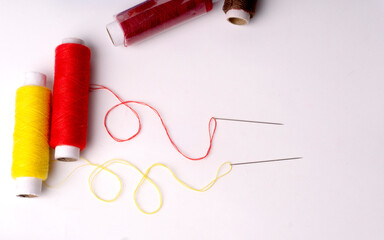 Colorful sewing thread set and needles isolated on background.