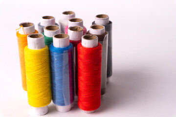 Colorful sewing thread set and needles isolated on background.
