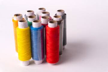 Colorful sewing thread set and needles isolated on background.