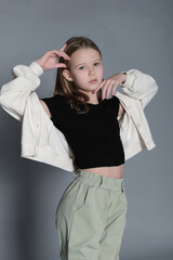Dressed in a casual black and white outfit, a young girl poses sideways, gazing at the camera with...