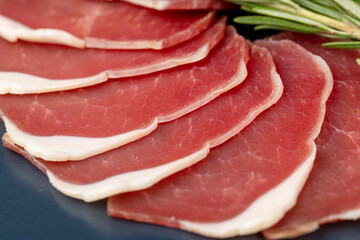 sliced ham with bacon on a board