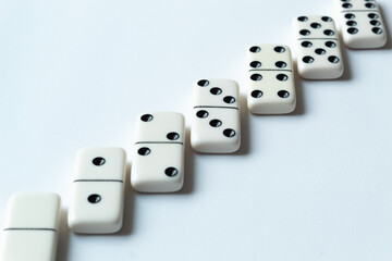 The game of dominoes is a table game involving rectangular pieces with dots that represent numbers. The objective is to match tiles with matching numbers. Photo with white background.