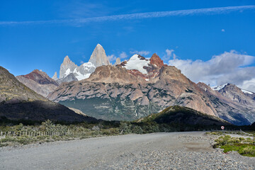 the striking Mount Fitz Roy in Patagonia, Argentina, with its jagged granite peaks and snow-capped summits set against a brilliant blue sky and rugged terrain.