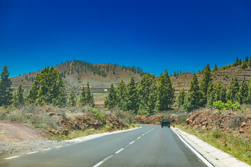 A scenic road leading towards a hilly landscape with sparse vegetation, Tenerife, Canary Island,...