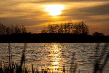 orange sunset is reflected in the water of the lake