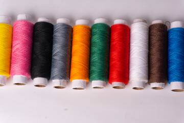 Colorful sewing thread set and needles isolated on background.