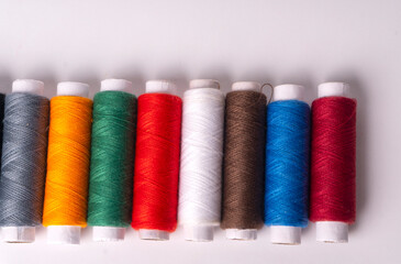 Colorful sewing thread set and needles isolated on background.