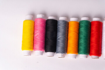 Colorful sewing thread set and needles isolated on background.
