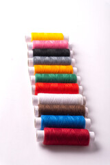 Colorful sewing thread set and needles isolated on background.