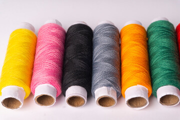Colorful sewing thread set and needles isolated on background.