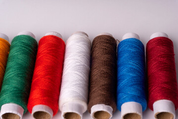 Colorful sewing thread set and needles isolated on background.