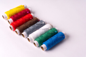 Colorful sewing thread set and needles isolated on background.