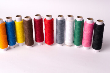 Colorful sewing thread set and needles isolated on background.