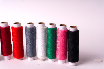 Colorful sewing thread set and needles isolated on background.