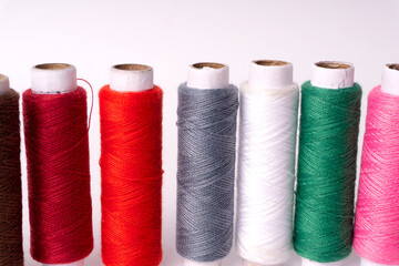 Colorful sewing thread set and needles isolated on background.