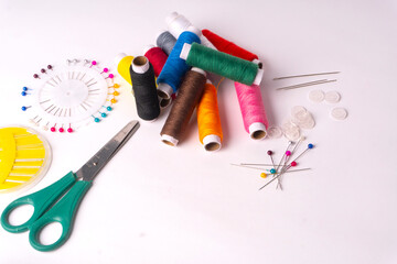 Colorful sewing thread set and needles isolated on background.