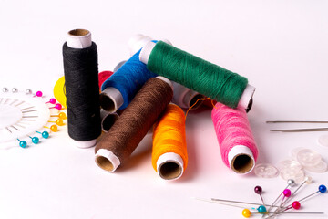 Colorful sewing thread set and needles isolated on background.
