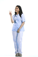 A female doctor, full-length, on a white background, shows a victory sign