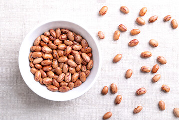 Cranberry beans, Borlotti beans in white bowl on linen. Tan colored, streaked with red variety of the common bean Phaseolus vulgaris, also known as Borlotto, Roman, saluggia, gadhra or rosecoco bean.