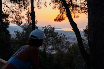 Woman viewing sunrise over Barcelona from forest vantage point