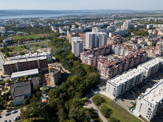 Obraz premium Aerial view of a densely populated urban area with tall residential buildings, colorful architecture, and parking lots. The cityscape showcases modern living in a busy neighborhood. Bulgaria, Varna