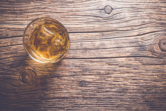 Whiskey glass on an old wooden table. Close up