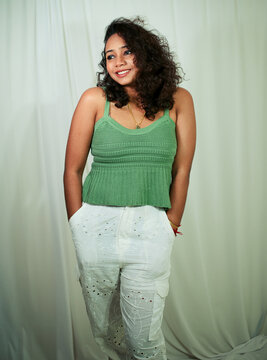 Fashion photoshoot of a young Indian woman with curly hair wearing a green dress.