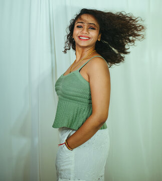 Fashion photoshoot of a young Indian woman with curly hair wearing a green dress.