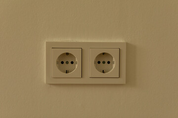 Two white electrical outlets on a beige wall
