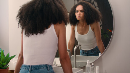 African American beautiful attractive female girl woman come in bathroom home looking at mirror...