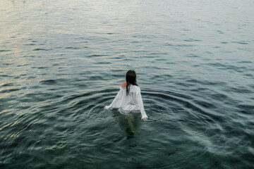 photoshoot of a girl wearing a wet white shirt and underwear on the sea