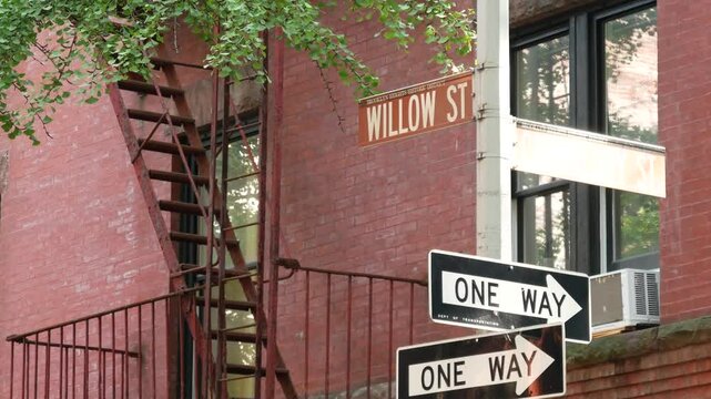 New York City crossroad, Brooklyn Heights Willow street intersection, one way road sign. Residential district architecture, red brick house, United States. Fire ladder and corner text roadsign.