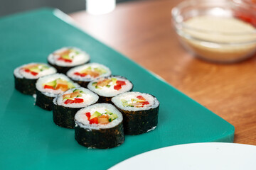 Freshly made sushi rolls with colorful vegetables sitting on a green cutting board