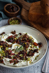 Cheese appetizer of goat cheese with bacon, dates, pistachio and rosemary on grey background close up