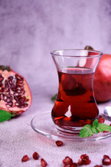 Turkish pomegranate tea in a glass glass and fresh pomegranate. Fresh mint and pomegranate seeds on the surface.