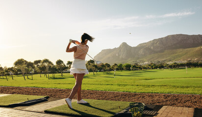 Woman enjoying golf practice at luxury scenic mountain resort on a sunny day in golf attire © Jacob Lund