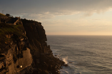 A dramatic cliff overlooking the vast ocean at sunset