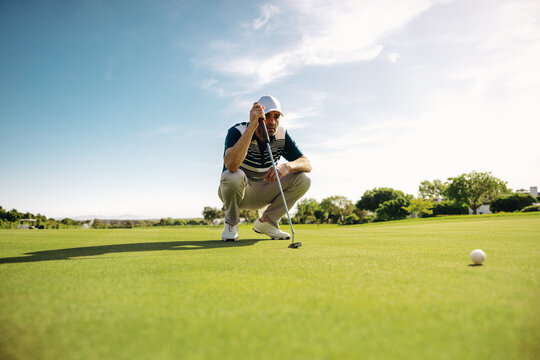 Close up of a focused male golfer lining up a putt on a scenic golf course