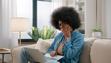 Worried African American woman stressed with laptop frustrated desperate shock sad upset reading bad negative news lost with computer at home couch girl business e-learning anxious financial problems