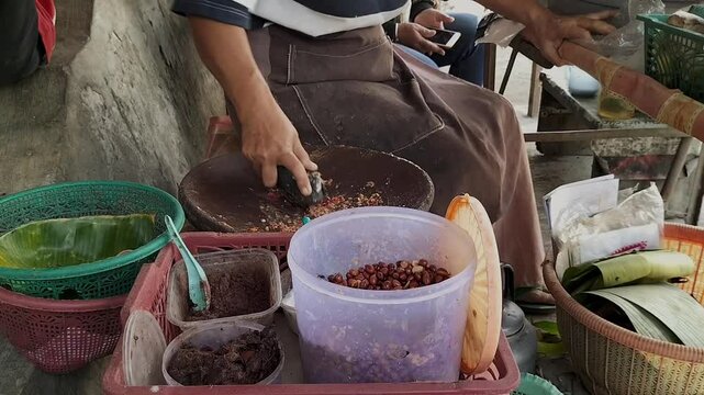 Ingredients for traditional Rujak seasoning from peanuts, soy sauce, chili peppers and petis. Preparing rujak petis. Footage.
