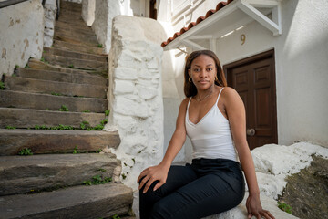 A woman is sitting on a rock in front of a white building