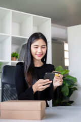 Happy Young Woman Shopping Online with Card and Phone in Cozy Home