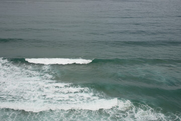 Fototapeta premium The ocean stretches out before you a deep blue canvas with a line of whitecaps breaking on the surface